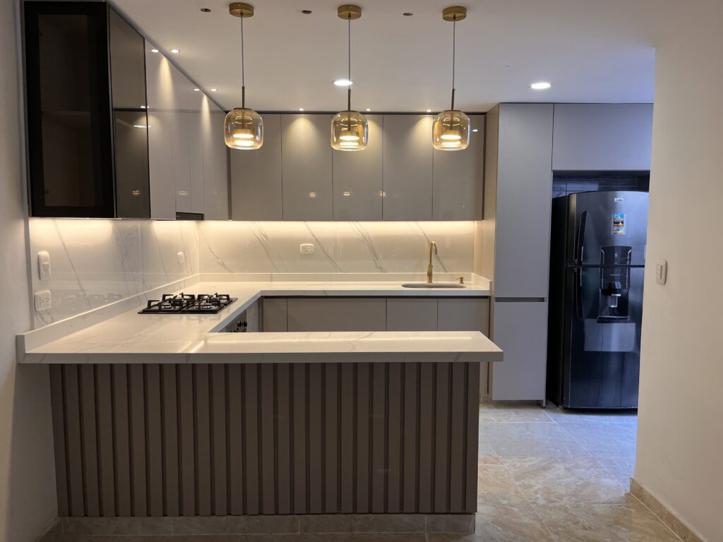 Cocina integral Color Ámbar Mate en la parte inferior, puertas superiores en Lamina Alto brillo, vitrina con luces led y puerta en aluminio con Vidrio Bronce y Mesón en Piedra Sinterizada.